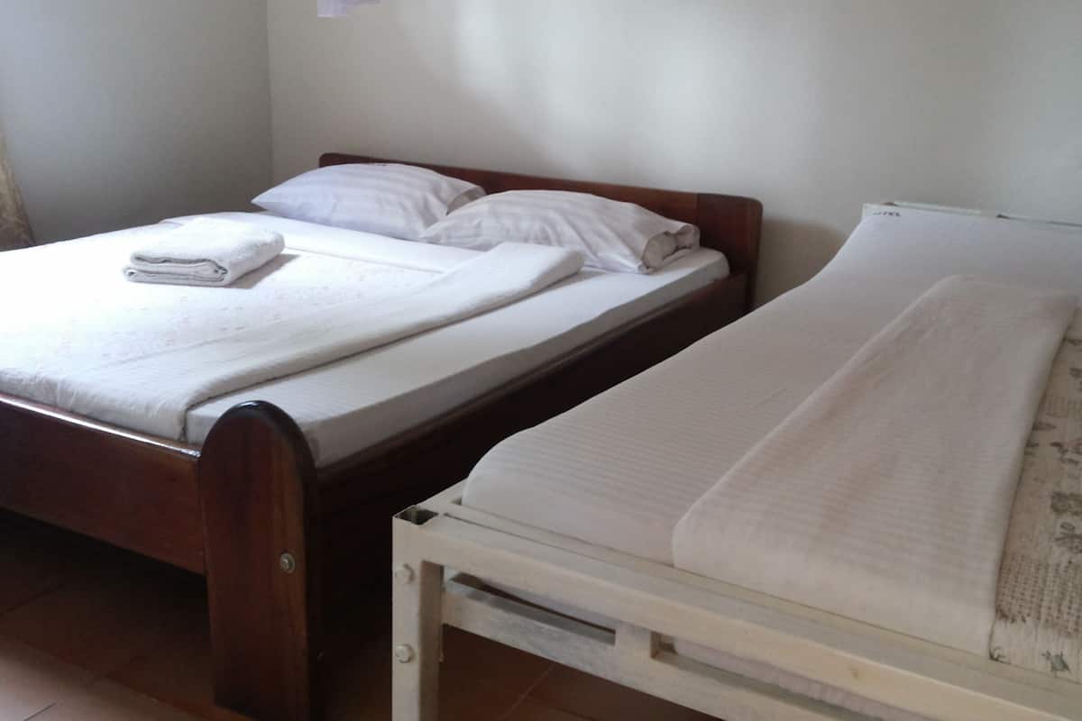 Dos camas en una habitación con cabecera de madera, colchones y mantas blancos.