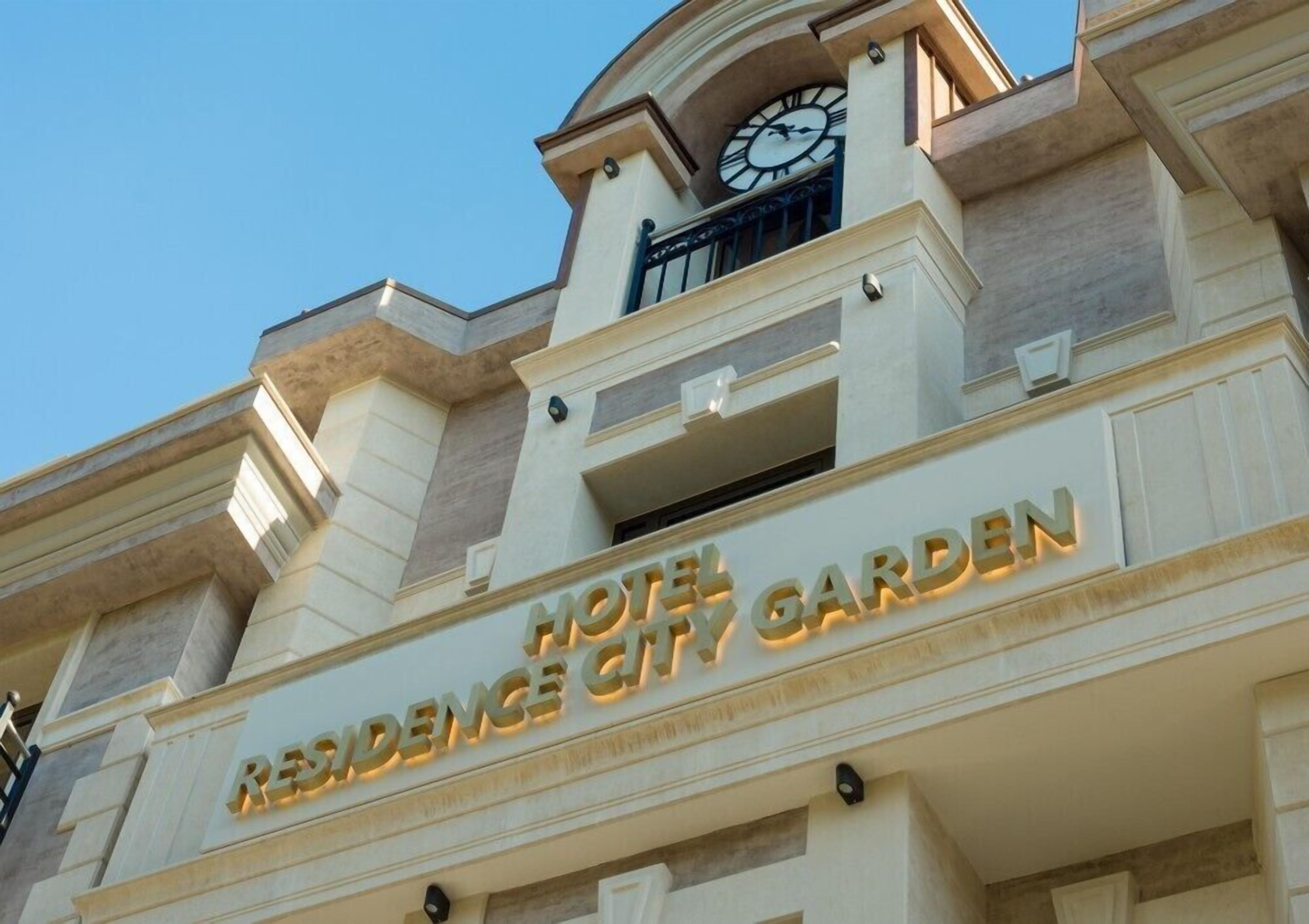 A hotel named "Residence City Garden" with a clock and a balcony.