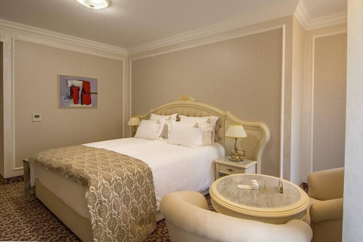 A hotel room with a large bed, a round table, and a chair.