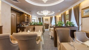 A hotel dining area with round tables, chairs, a chandelier, and potted plants. - Residence City Garden (Plovdiv)