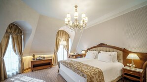 A well-appointed bedroom with a large bed, a chandelier, and a nightstand with a lamp. - Residence City Garden (Plovdiv)