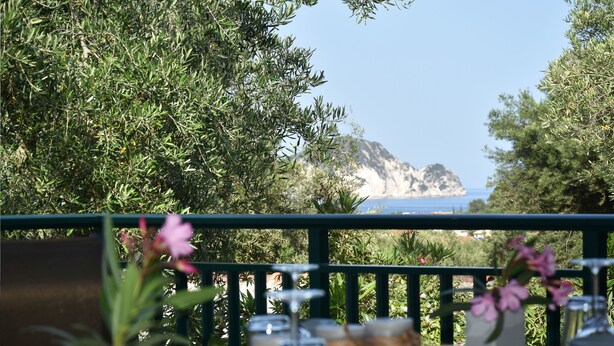 Una mesa con vista al mar y una isla rocosa al fondo.