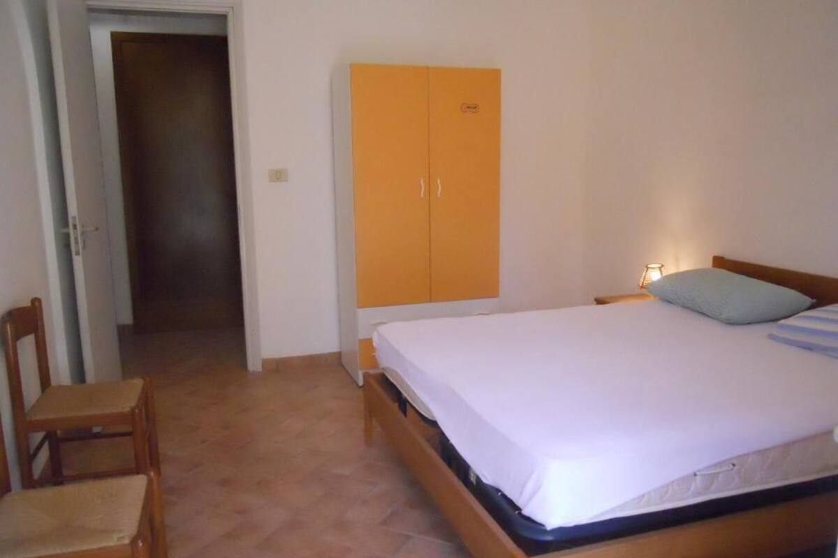 Une chambre à coucher comprenant un lit, une armoire, une chaise et une porte donnant sur une autre pièce.