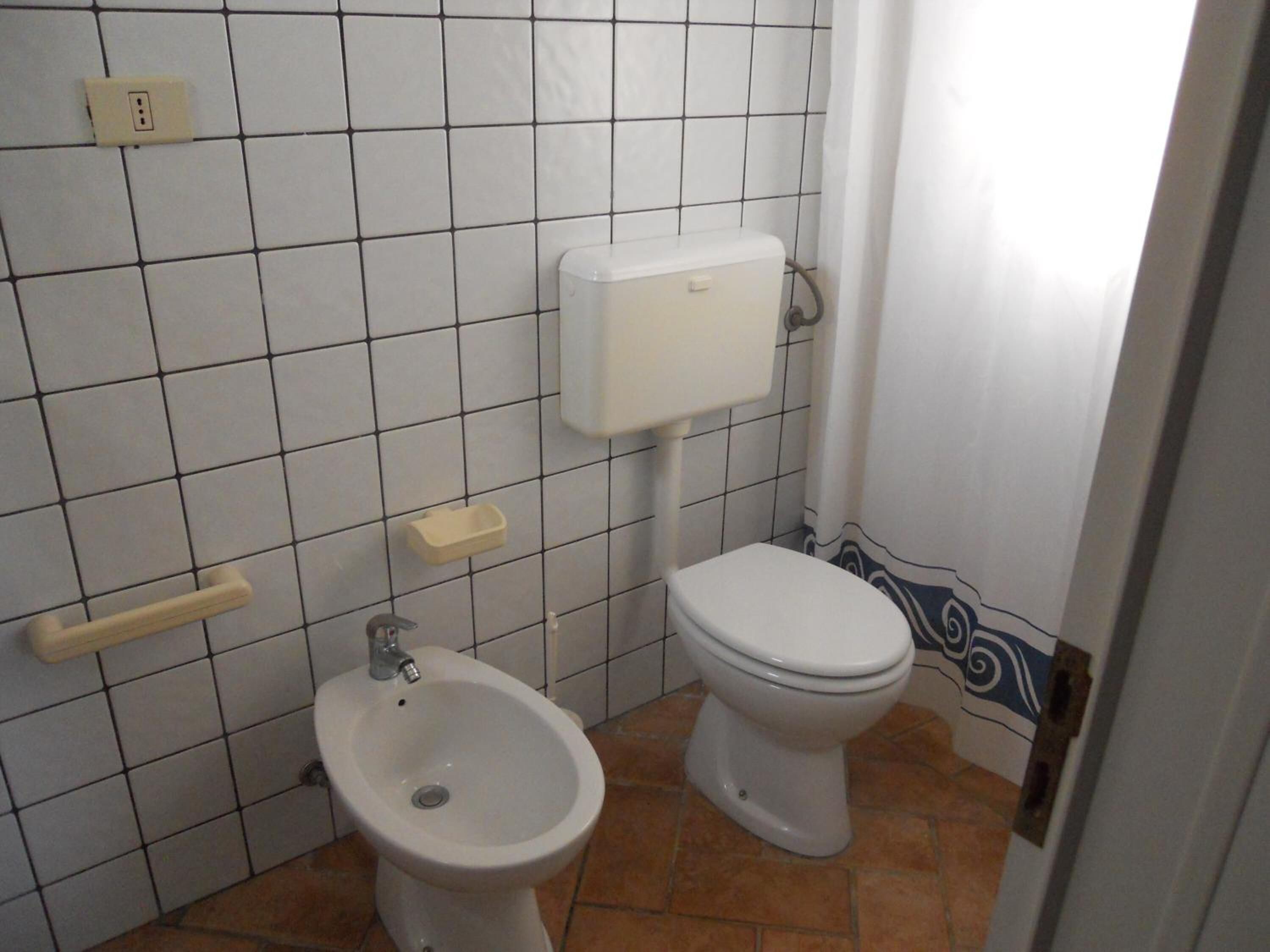 A bathroom with a toilet, bidet, and a towel rack.