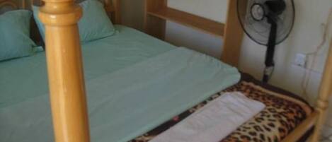Una cama con cabecera de madera, cubrecama estampado de leopardo y toalla blanca.