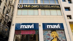 Un immeuble portant l’enseigne « Blue Para Istanbul Hotel » et deux devantures de magasins « mavi » en dessous.