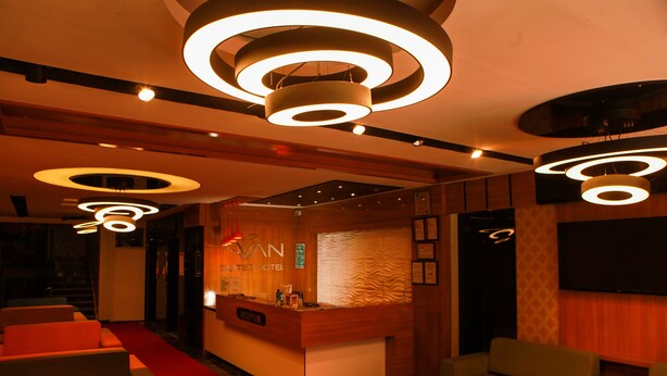 A hotel reception area with a modern design, featuring a reception desk, seating area, and circular lighting fixtures. - Van Hotel (Van)