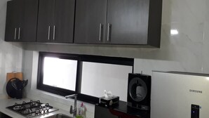 Una cocina con armarios oscuros, una estufa a gas, un refrigerador Samsung y una ventana sobre el fregadero.