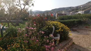A garden with various flowers and a white bird sculpture. - Apartments Dalmatinka Metajna Novalja (Novalja)