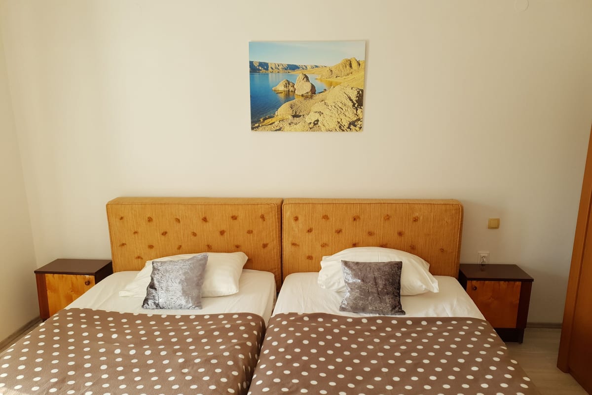 Una cama doble con colcha de lunares, dos almohadas y cabecera de madera.