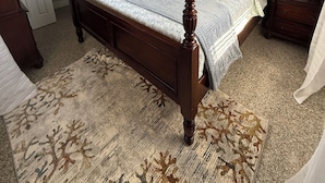 A four-poster bed with a ceiling fan, a patterned rug, and a nightstand with a lamp. - Amazing beach getaway! (Redington Beach)