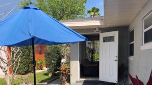 A patio area with a blue umbrella, a round table, and two benches. - Amazing beach getaway! (Redington Beach)