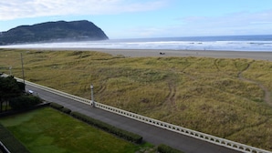 Eine Küstenlandschaft mit einer Wiese, einem gepflasterten Weg und Blick aufs Meer.