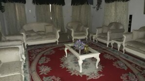 Una sala de estar con alfombra roja, dos sofás y tres sillones.