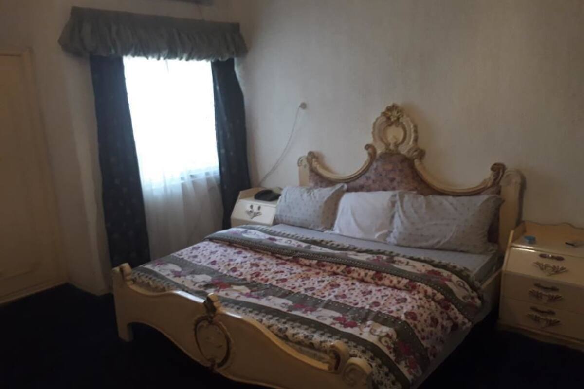 Ein Schlafzimmer mit einem Bett, einem Nachttisch, einer Kommode und einem Fenster mit Vorhängen.
