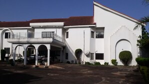 Un edificio blanco con techo rojo, una entrada cubierta con columnas y una antena parabólica.