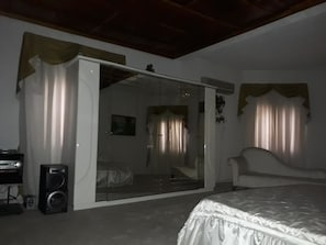 A bedroom with a bed, a large mirror, a wardrobe, and a speaker. - Hatfield Hotel (Mongu)