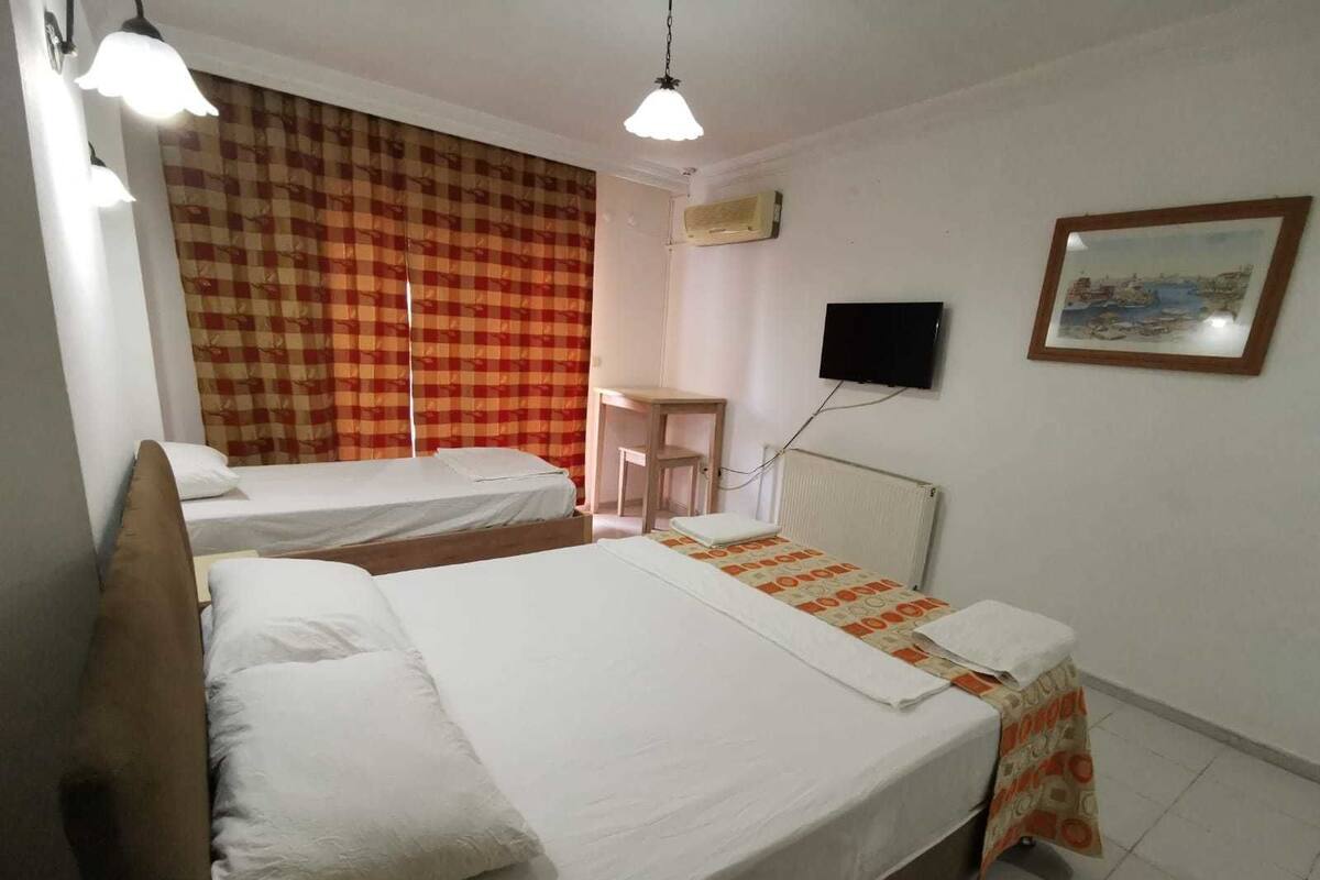 A hotel room with two beds, a desk, a chair, a television, and a painting on the wall.