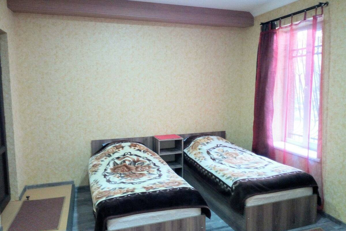 A room with two single beds, a small table, and a window with curtains.