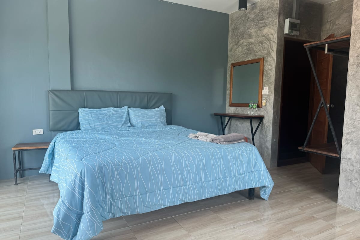 Une chambre à coucher avec un lit, une table de chevet, un miroir et une porte.