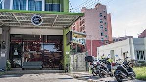 A hostel with a green facade, a signboard, and a motorcycle parked in front.
