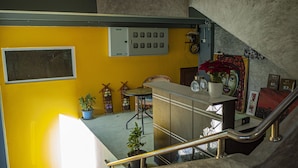 A staircase with metal railings leading to a landing with a yellow wall, a small table with chairs, and a potted plant.