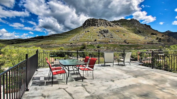Une terrasse extérieure avec une table et des chaises, offrant une vue sur un paysage montagneux.
