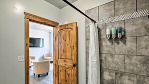 Une salle de bain avec un rideau de douche, une porte en bois et un mur carrelé.