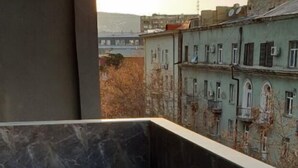 A balcony with a tiled floor and a view of buildings in the background. - Apartment on Kandelaki Str. (Tbilisi)