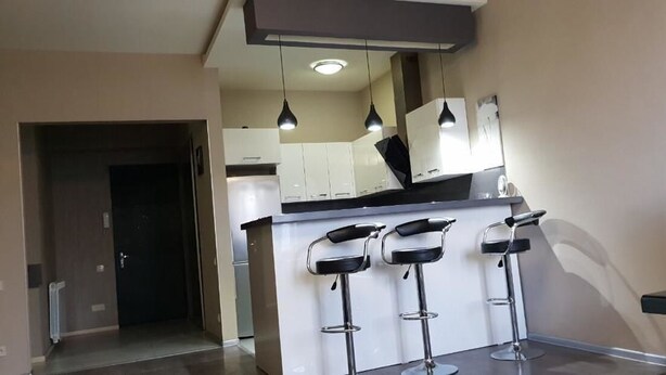 A modern kitchen with three bar stools, a refrigerator, and pendant lighting. - Apartment on Kandelaki Str. (Tbilisi)