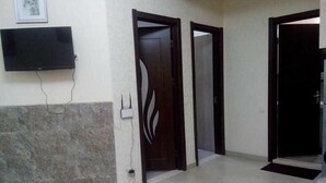 A hallway with a tiled floor, a flat-screen TV mounted on the wall, and a door with a decorative design. - Apartment on Kandelaki Str. (Tbilisi)