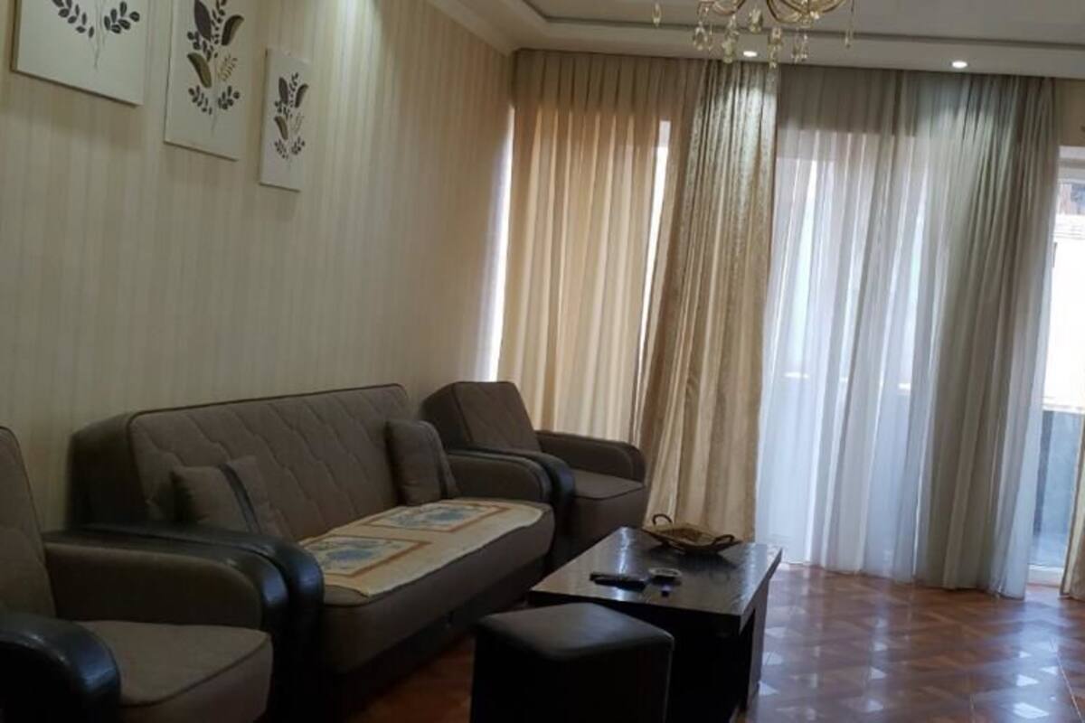 Een woonkamer met een bank, fauteuils, een salontafel en een televisie.