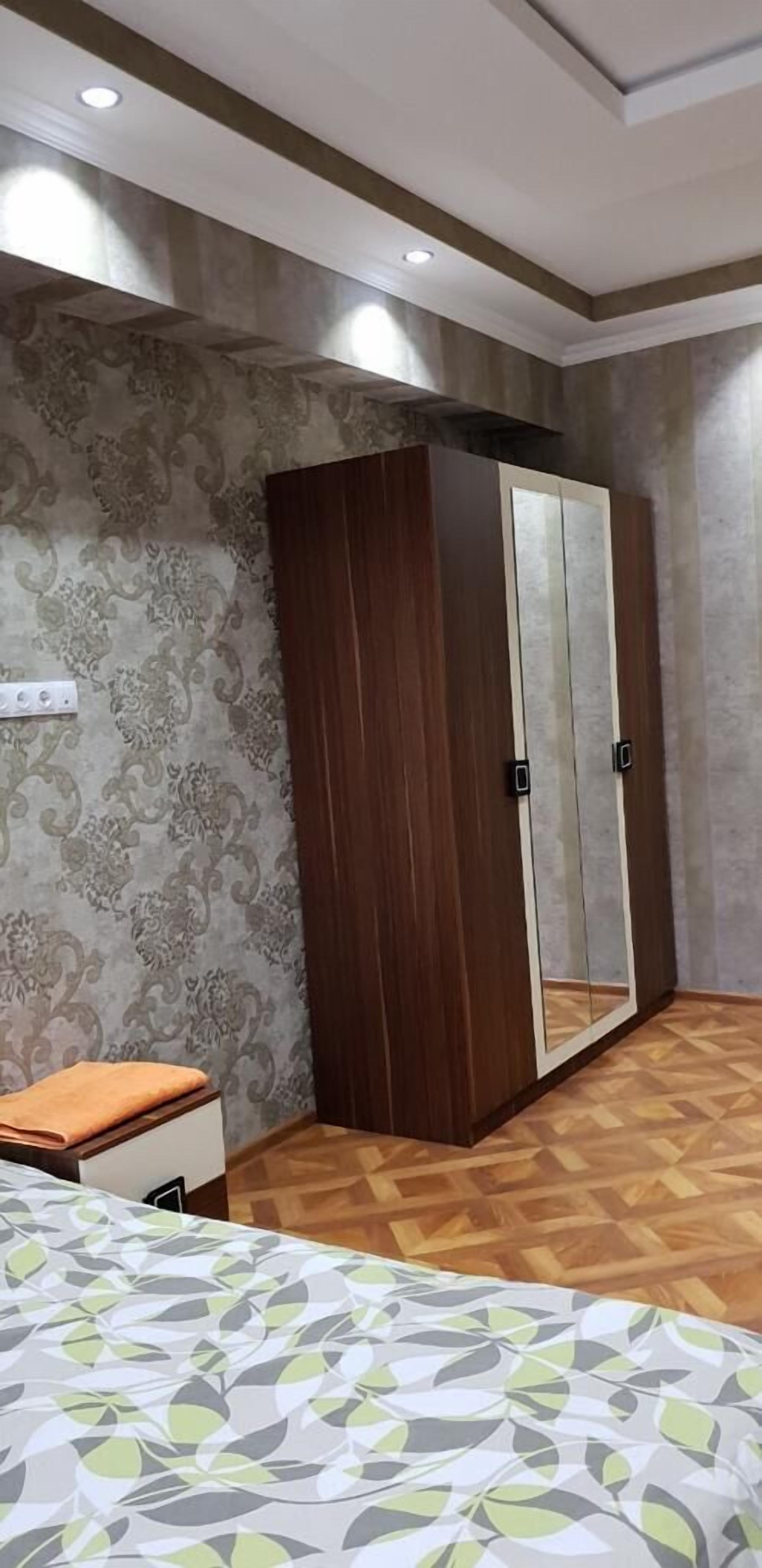 A bedroom with a bed, a wardrobe, and a mirror.