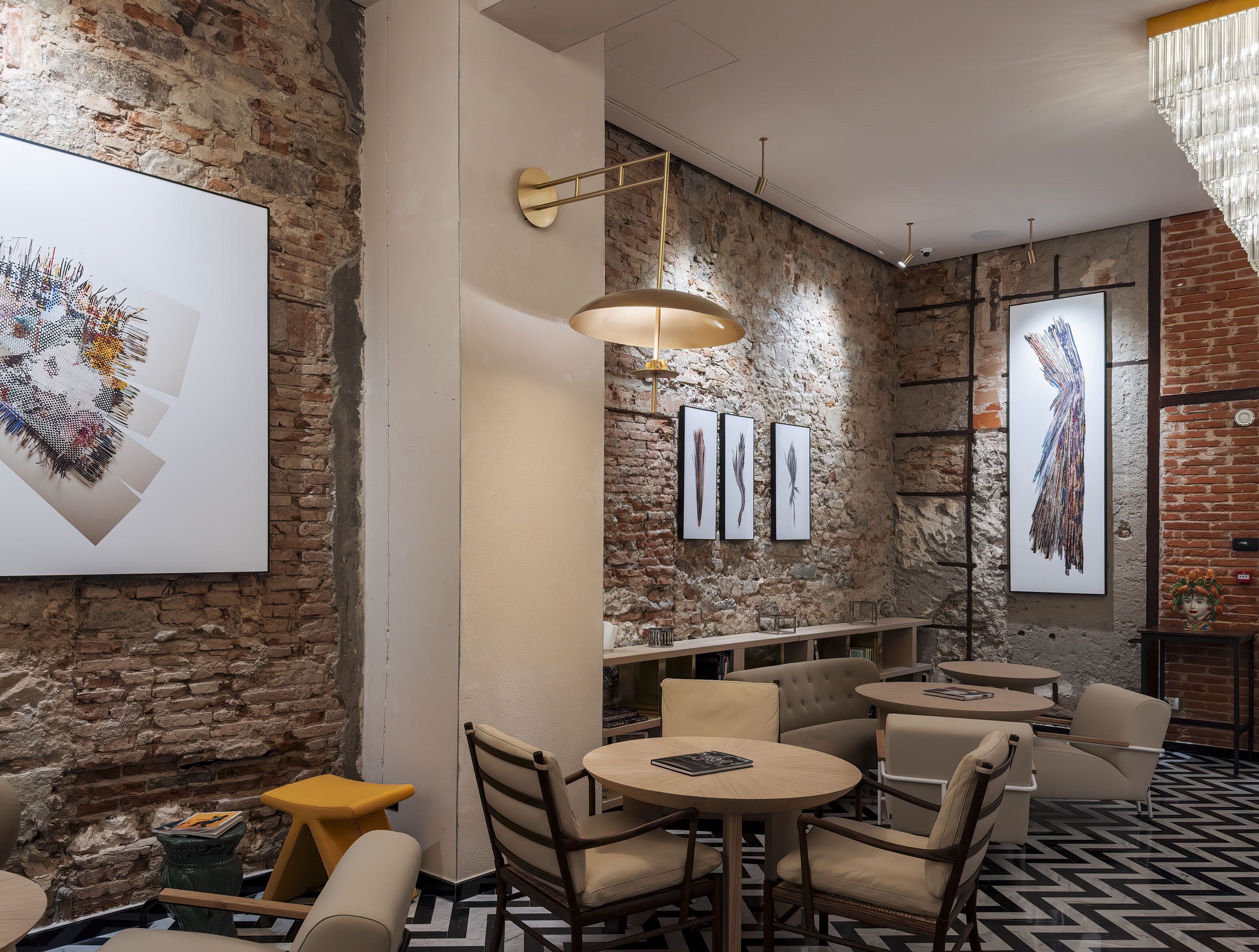 A modern interior with exposed brick walls, round tables, and comfortable seating.