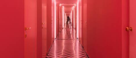 A long, narrow hallway with a chevron-patterned floor and pink walls.