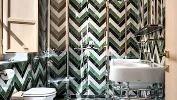 Un baño moderno con suelo de diseño en zigzag, cabina de ducha de vidrio y lavamanos blanco.
