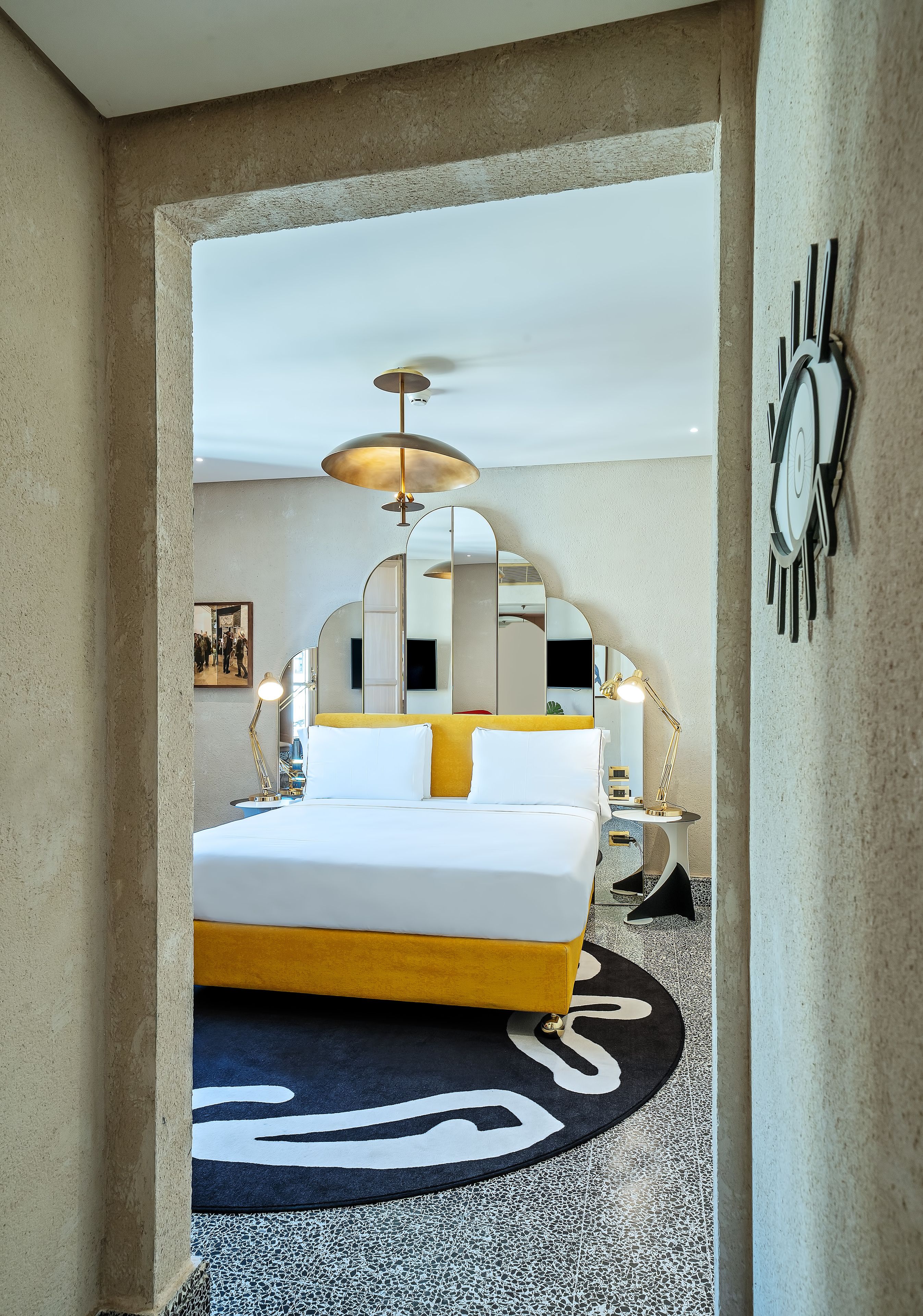 Una habitación de hotel moderna con una cama grande, un ventilador de techo y una alfombra redonda.
