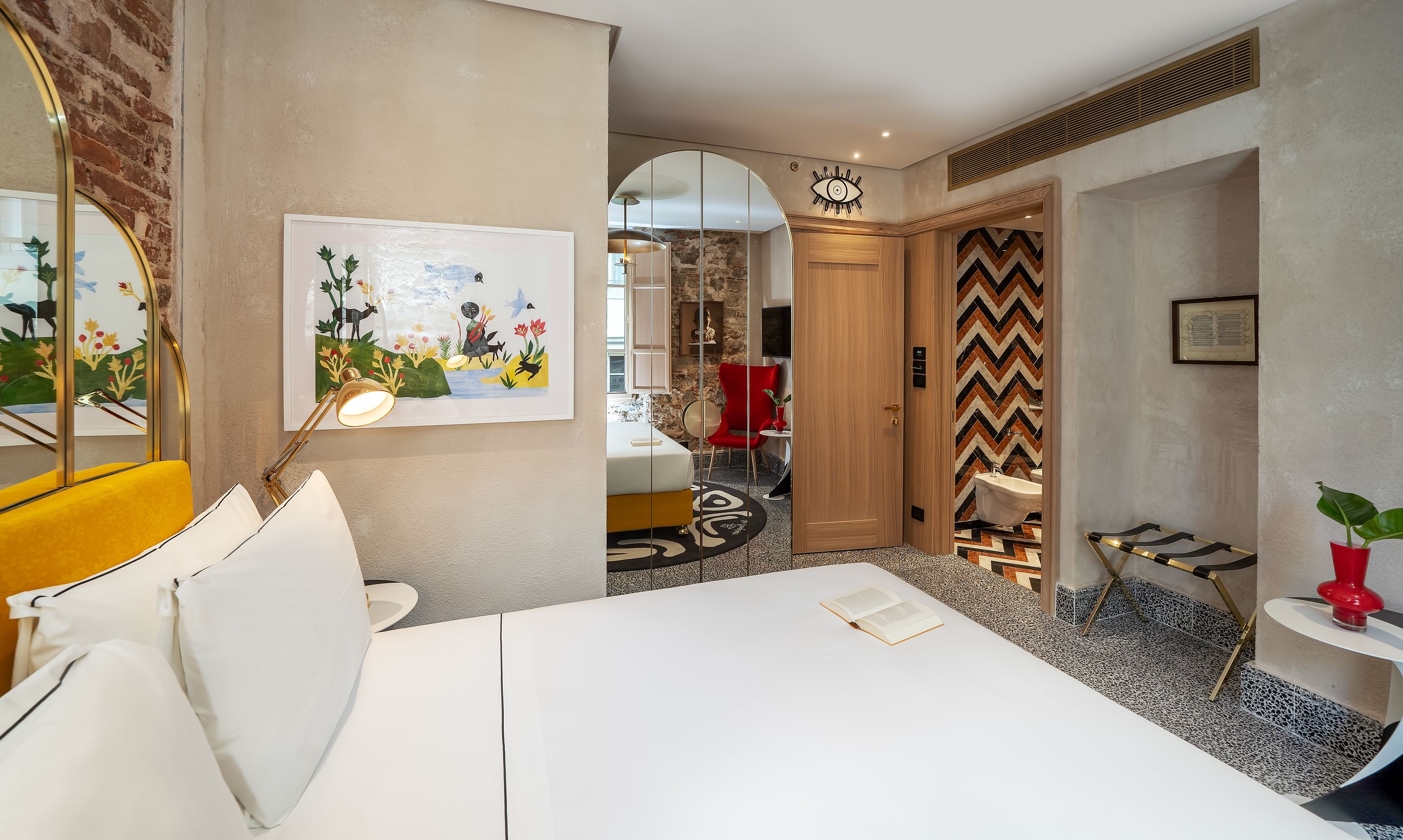 Una habitación de hotel moderna con cama, escritorio, silla y baño visible a través de un arco.