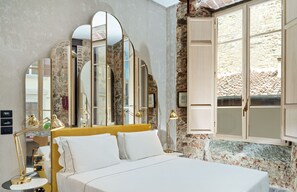 A bedroom with a bed, a desk, and a large window with stone walls. -  Hotel Calimala Florence (Florence)