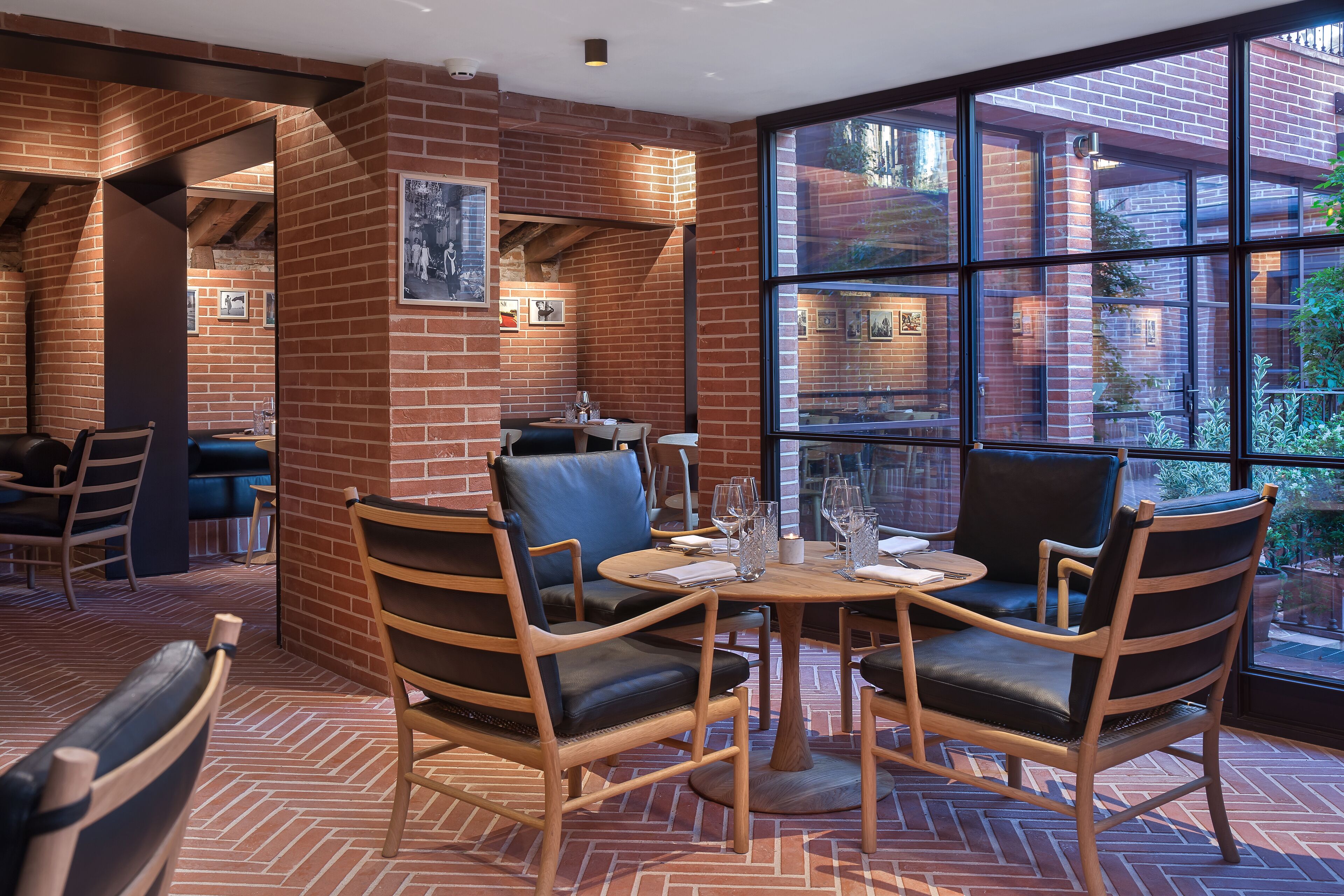 A restaurant with brick walls, large windows, and wooden furniture.