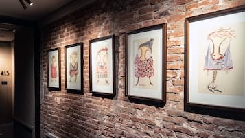 A hallway with a brick wall and framed artwork.
