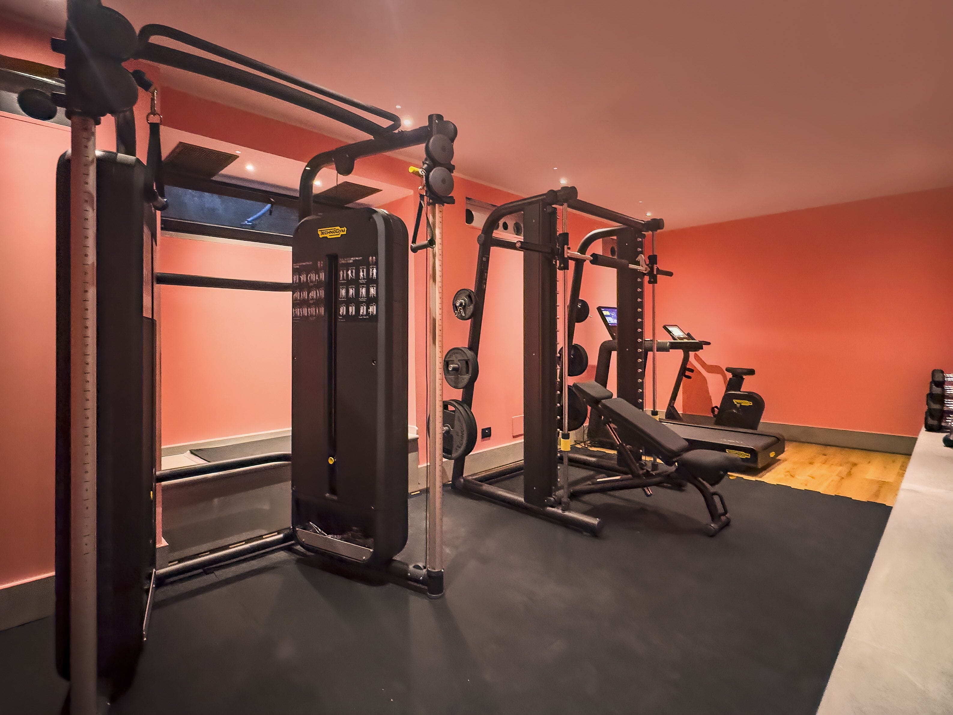 A gym with weightlifting equipment, a bench, and an exercise bike.