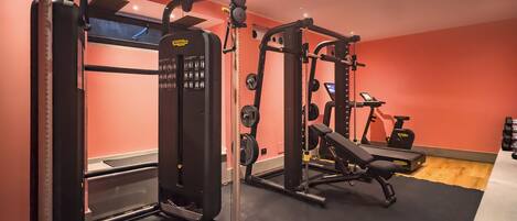 A gym with weightlifting equipment, a bench, and an exercise bike.