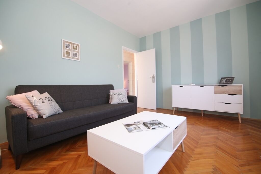 A modern living room with a grey sofa, white coffee table, and a white cabinet.