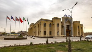 A building with a prominent entrance and multiple flags. - Hotel Erkin Palace (Khiva)