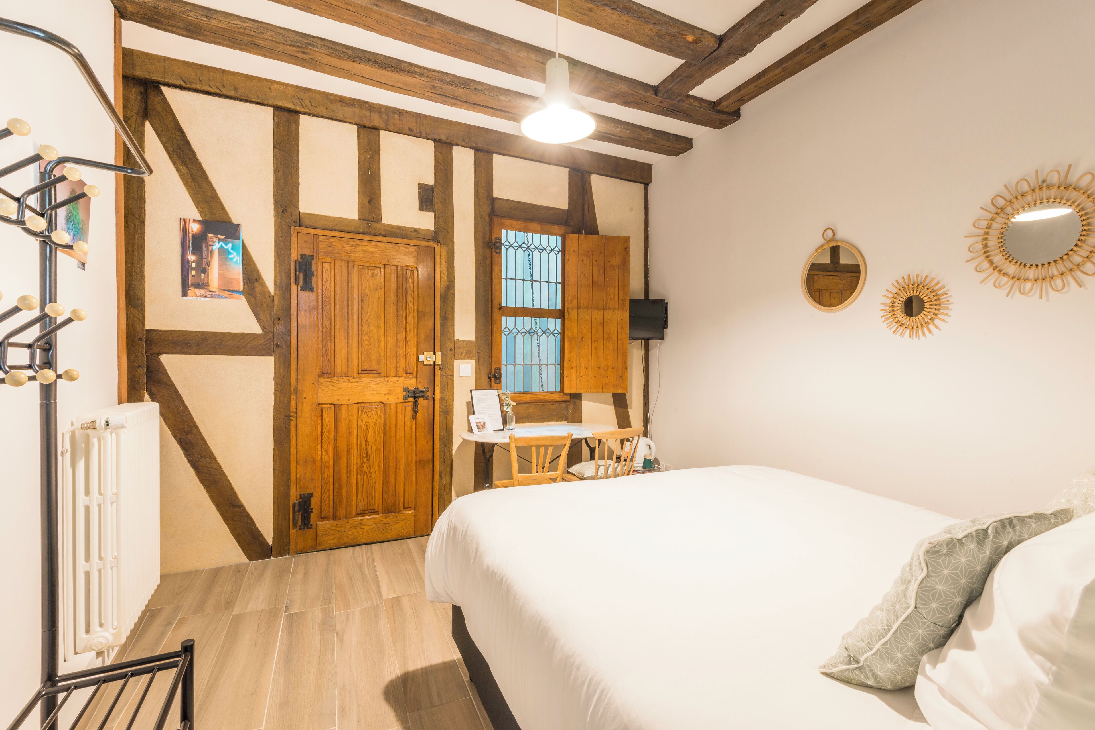 A bedroom with a bed, a wooden door, a small table, and a chair.