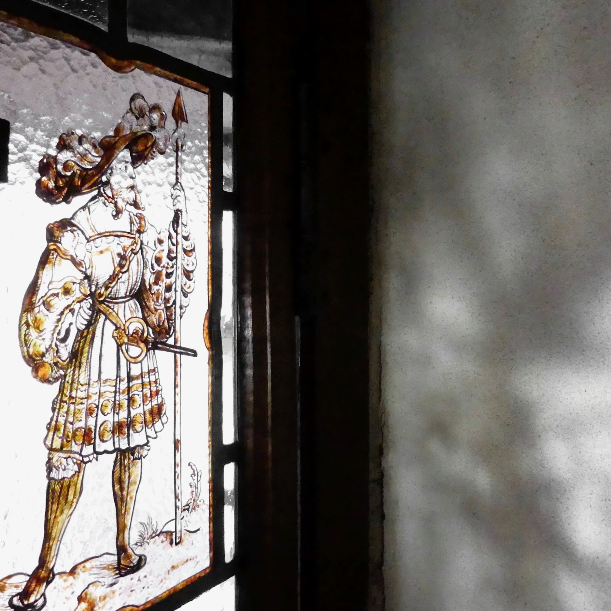 A stained glass window with a figure holding a staff and a flag.