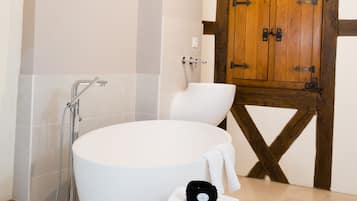 Ein Badezimmer mit einer großen Badewanne, einem Holzschrank und einem Holzschemel.