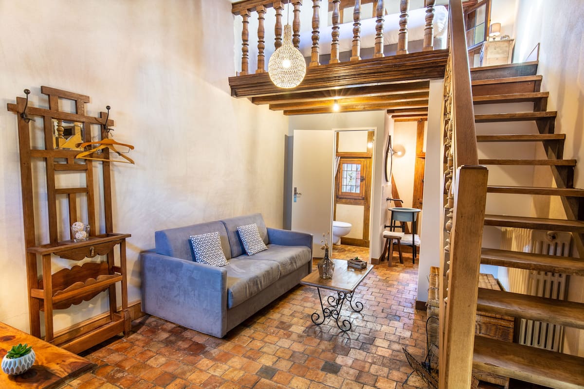 A cozy living area with a blue sofa, wooden shelves, and a staircase.