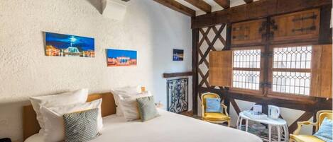 Ein Schlafzimmer mit einem großen Bett, Holzbalken, einem kleinen Tisch und Stühlen.